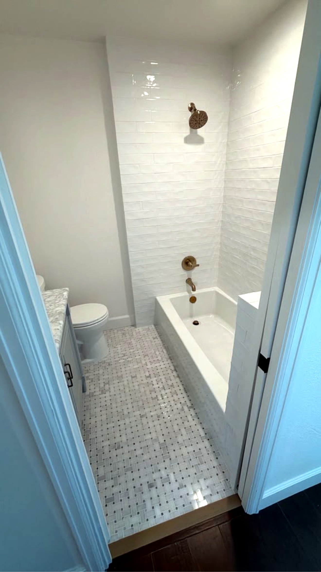 Finished bathroom viewed from the doorway, brass fixtures, marble mosaic floor