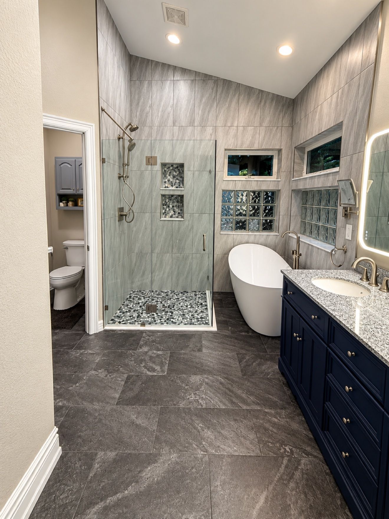 Remodeled primary bathroom with walk-in glass shower, freestanding soaking tub and custom double vanity