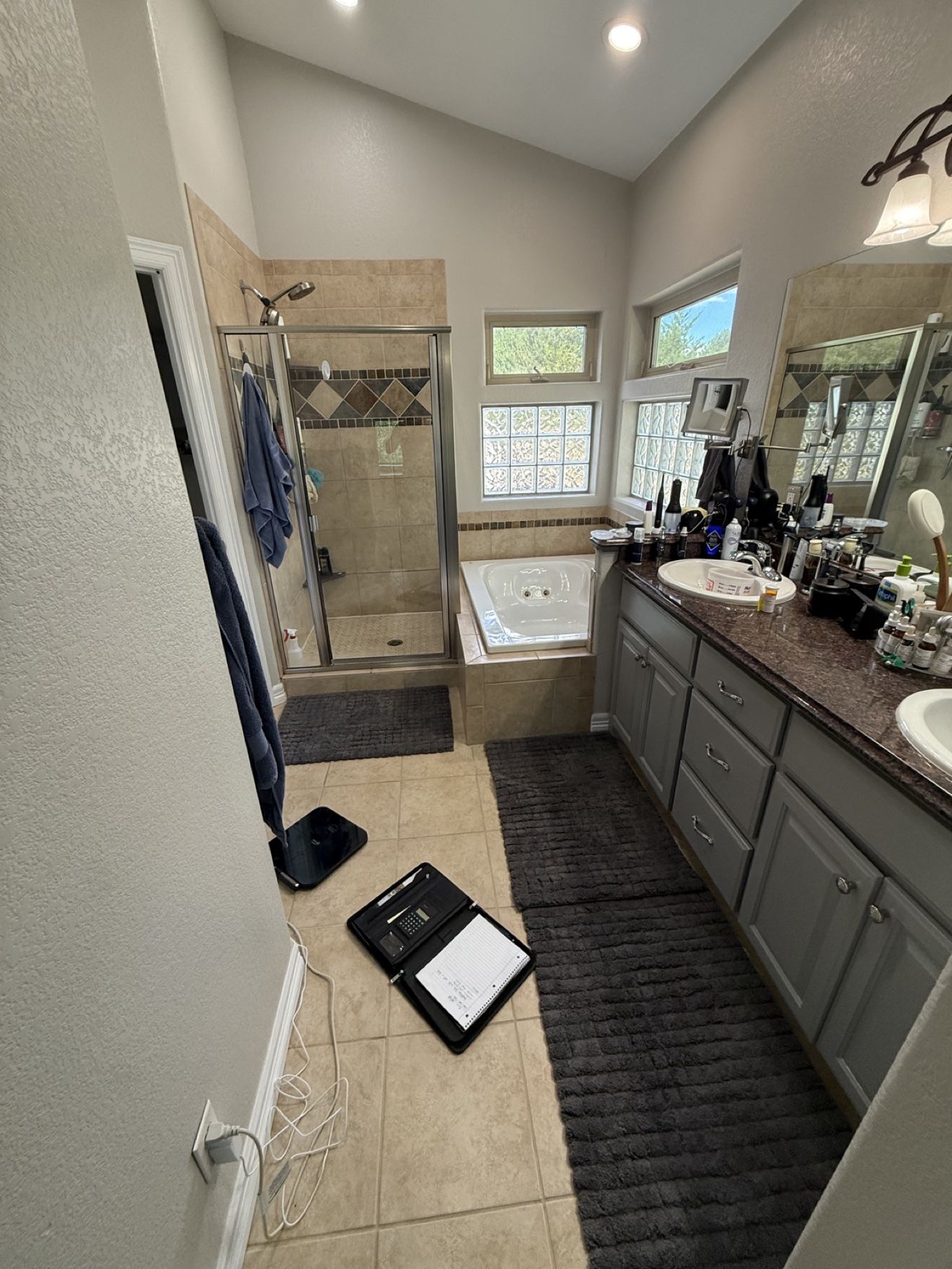 Primary bathroom before remodeling — dated corner tub, small separate shower stall and double vanity