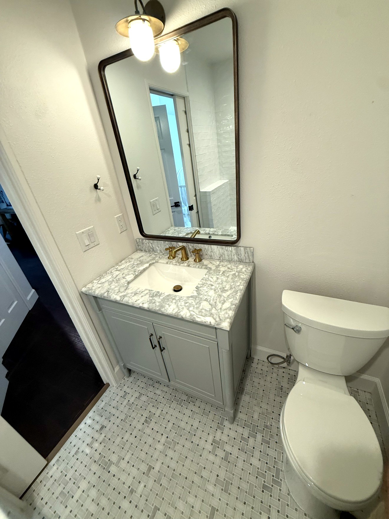 Gray vanity with marble top, brass faucet and framed mirror